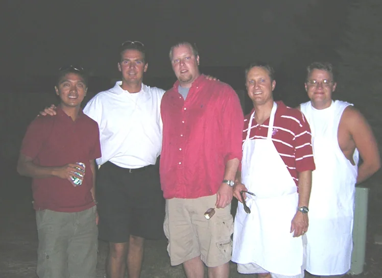 Five members of the Pig Crew photographed at night, one in a white chef apron