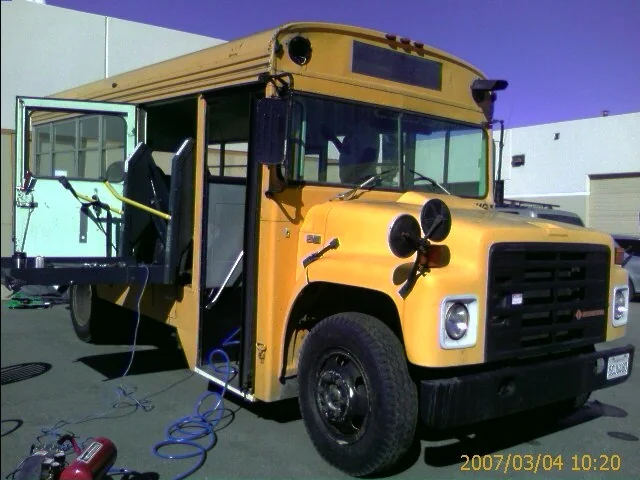 The original yellow Bluebird school bus parked in a lot before the conversion