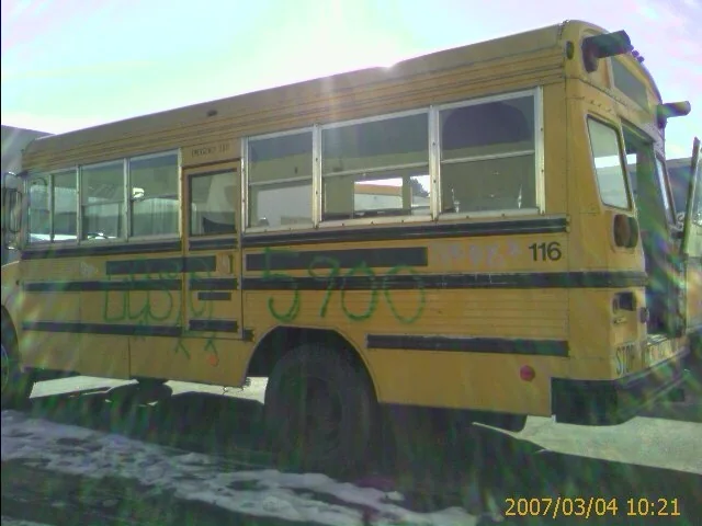 The original yellow Bluebird school bus parked in a lot before the conversion