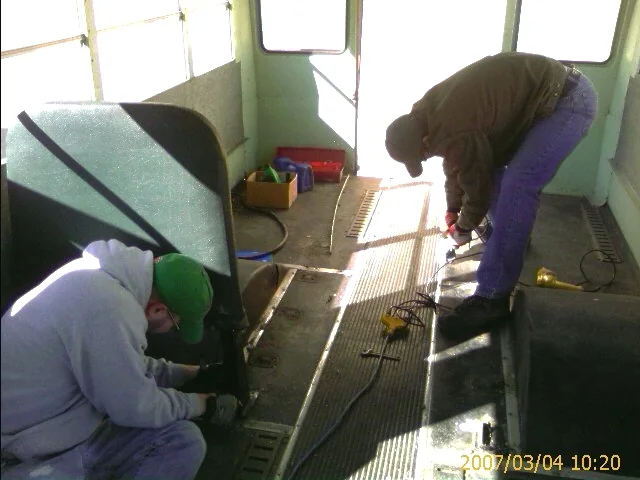 Crew members stripping the old school-bus seats and flooring out of the bus