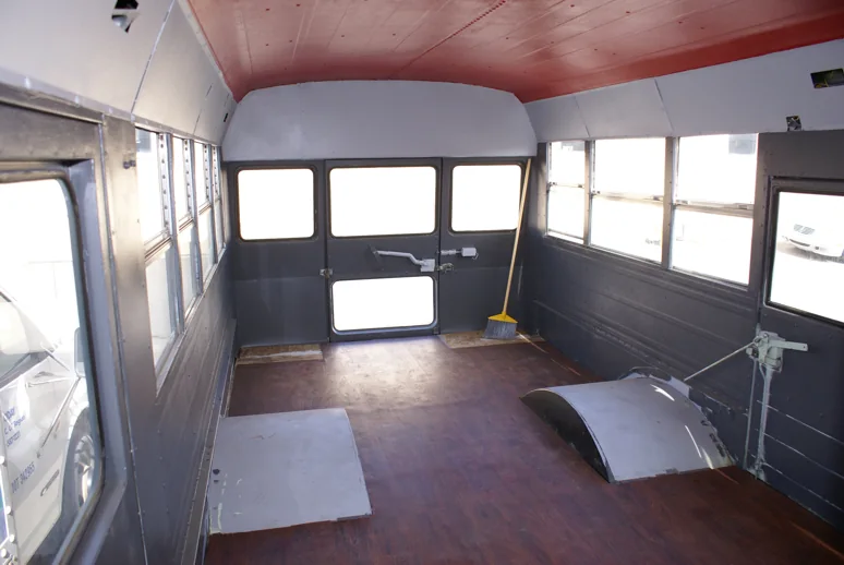 The stripped bus interior with new gray walls, red ceiling and wood-look floor
