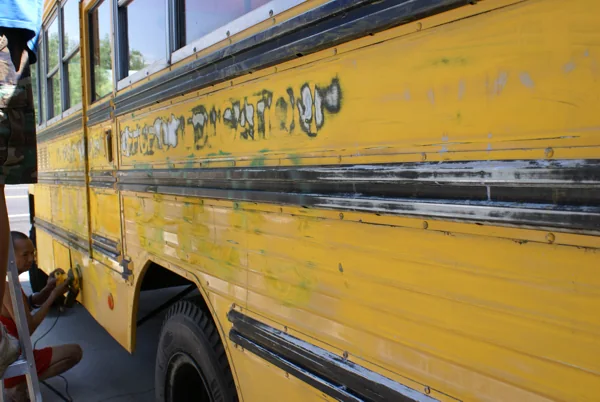 The yellow bus at the house, being sanded and taped for paint