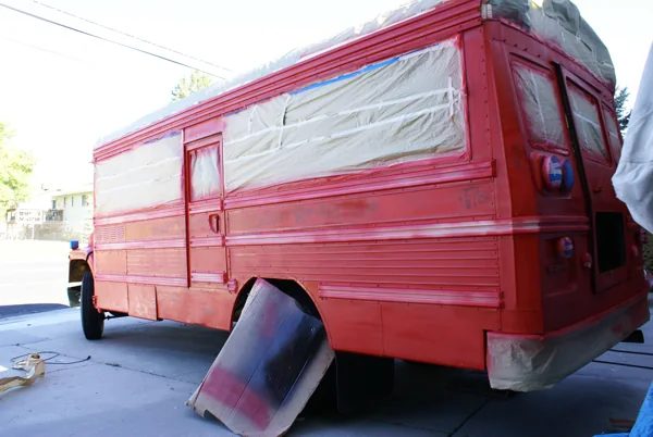 The bus freshly sprayed red with windows and grille still masked