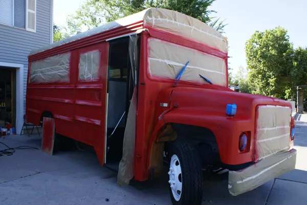 The bus freshly sprayed red with windows and grille still masked