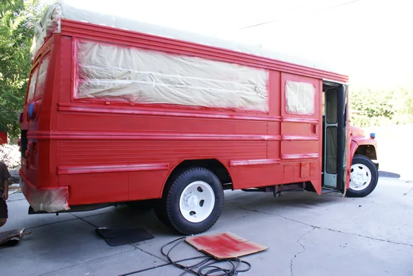 The bus freshly sprayed red with windows and grille still masked