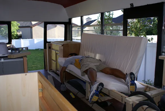 A crew member stretched out testing a newly built bench inside the bus