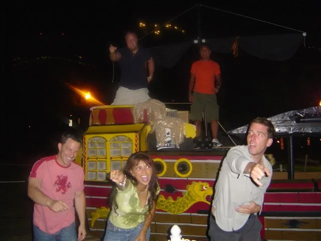 The crew posing at night in front of a pirate ship float