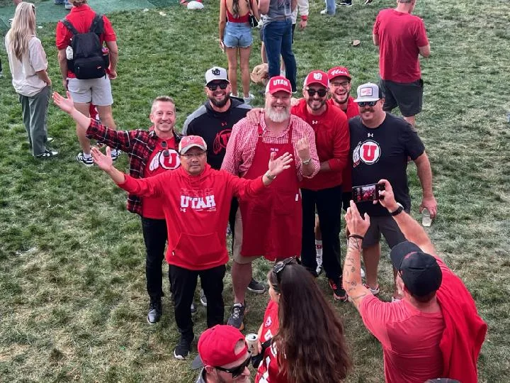 Crew and friends in Utah red posing for a group photo on the grass at the tailgate