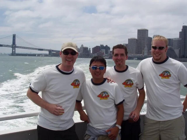 Four friends in matching team shirts on a boat on San Francisco Bay