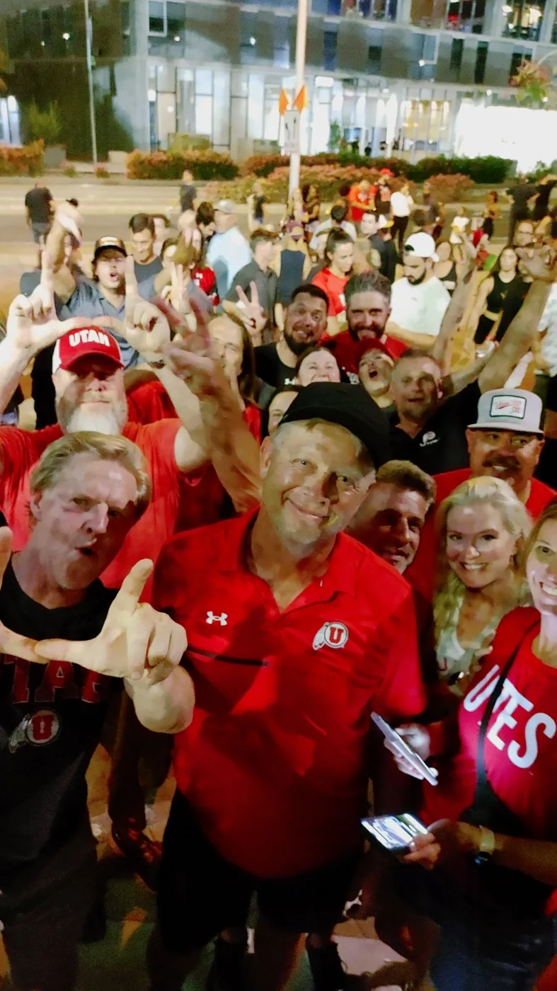 A crowd of Utah fans throwing the U in a night selfie