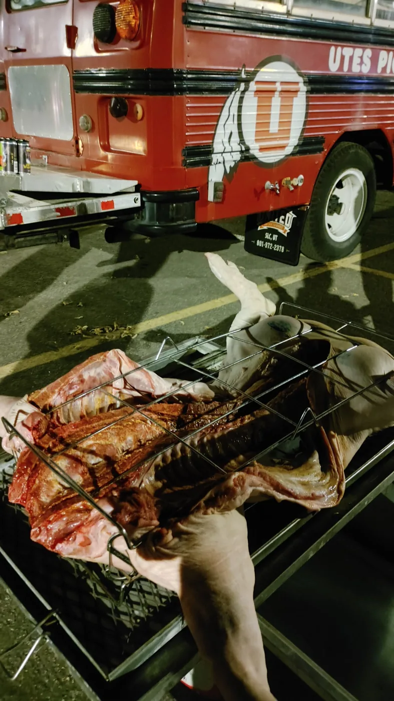 A whole pig clamped in a grill rack beside Porky at night