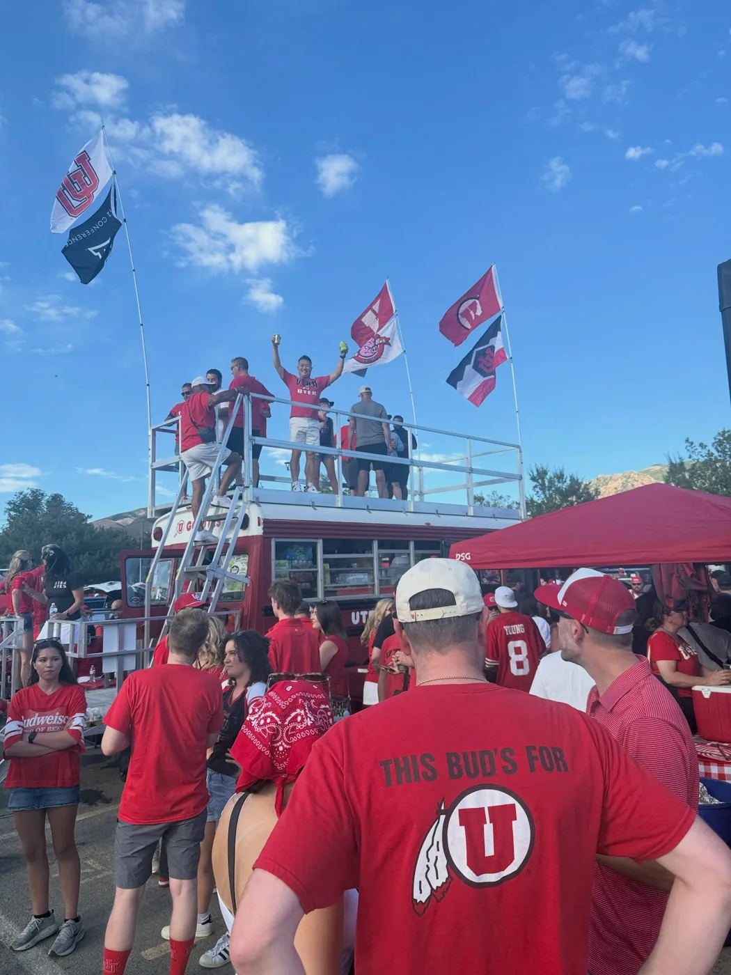 Fans cheering on Porky’s roof deck under Utah and Pig Bus flags