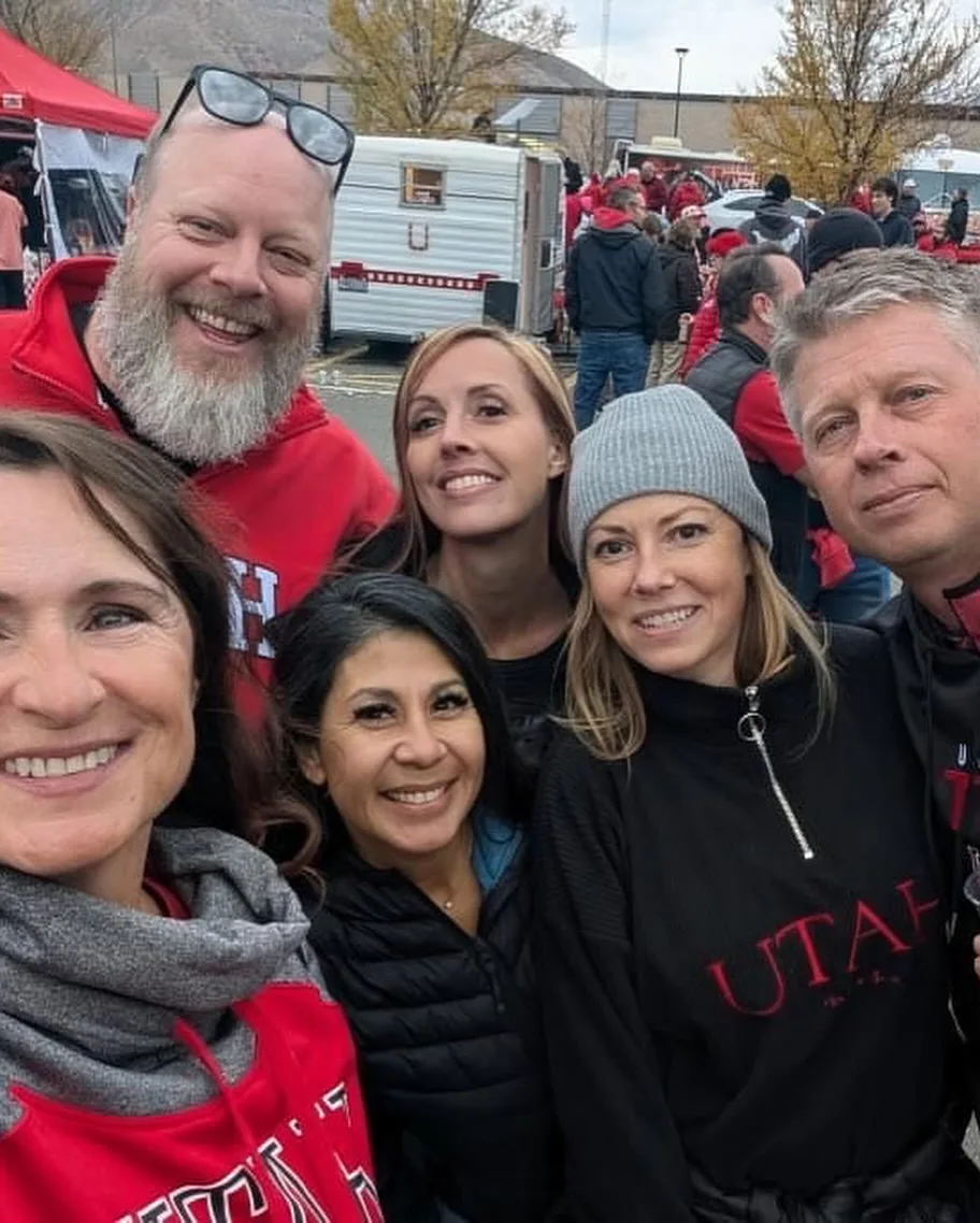 Friends bundled up in Utah gear for a selfie at a cold tailgate