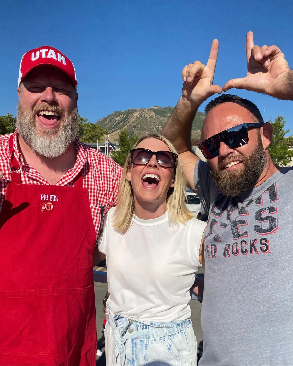 Three friends laughing and throwing the U, mountains behind