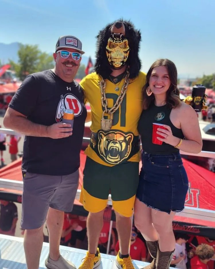 A crew member and a fan with a visiting-team superfan in a gold mask and chain