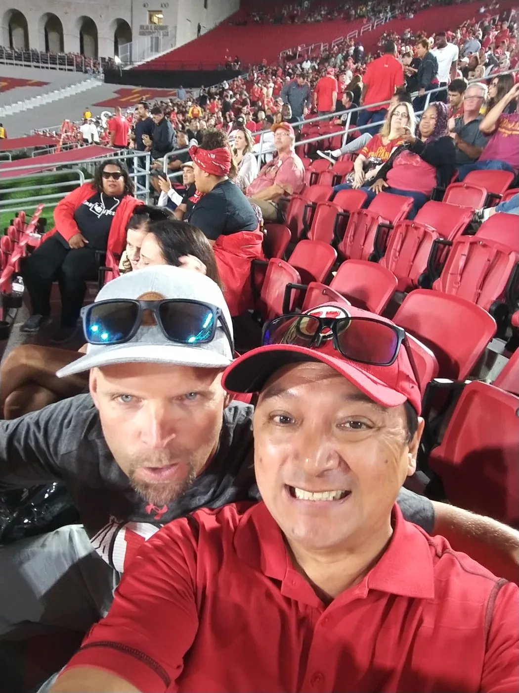 Two crew members taking a selfie in the stands at the Los Angeles Memorial Coliseum