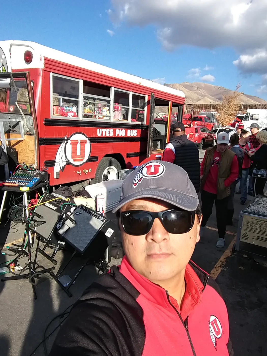 A crew member’s selfie beside Porky with amps and a mixing board set up in the lot