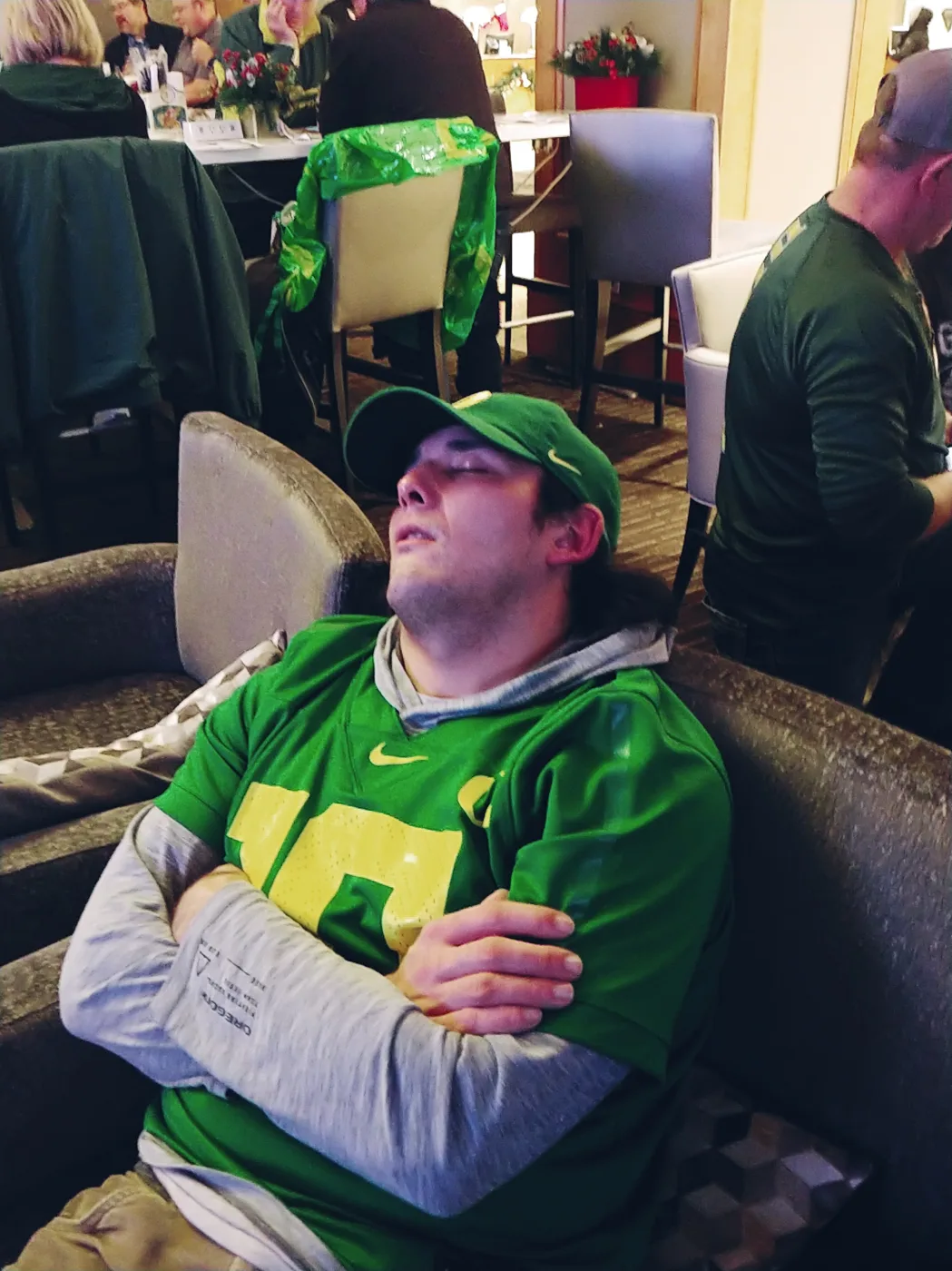 An Oregon fan in a green jersey napping in a lounge chair