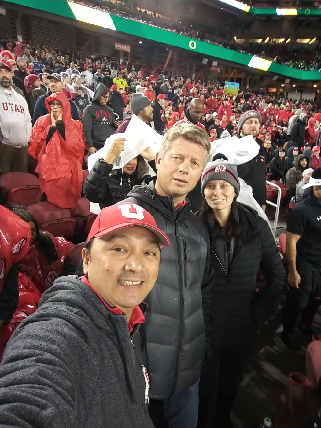 Three Utah fans in the stands at a rainy night game at Levi’s Stadium